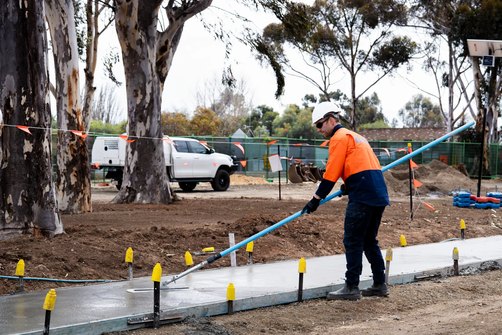 Crew forming and placing concrete kerb along a road