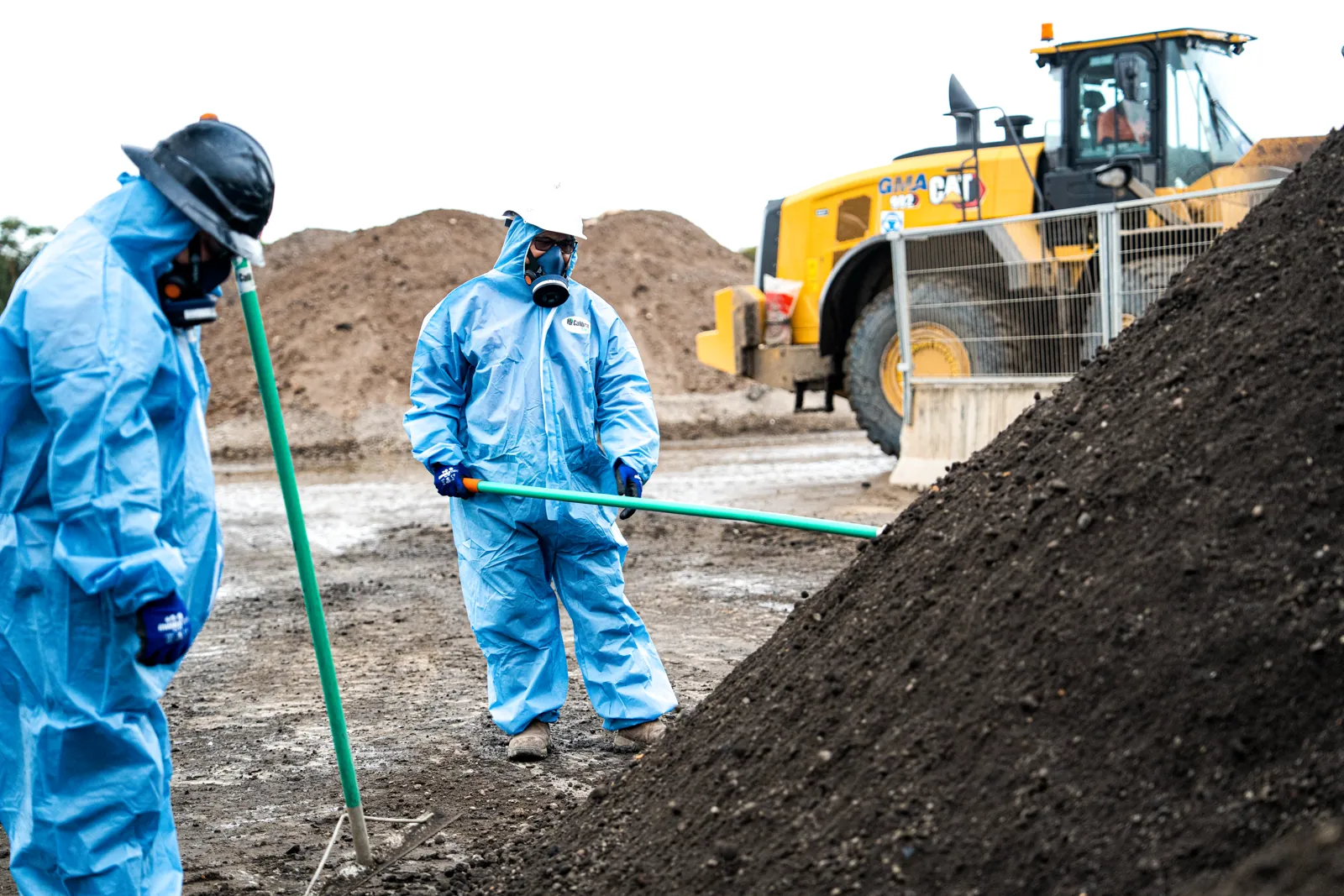 Crew in protective suits working with screened material
